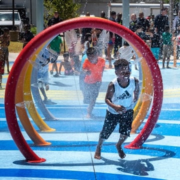 Child running through Essentials Spray Features for a water play area