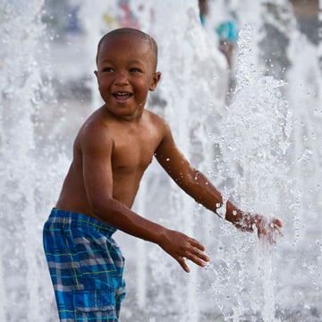 Child playing with ground spray water park equipment